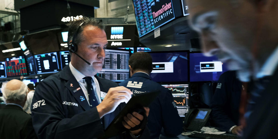 a man holding a phone: US stocks edge lower as earnings fail to impress investors